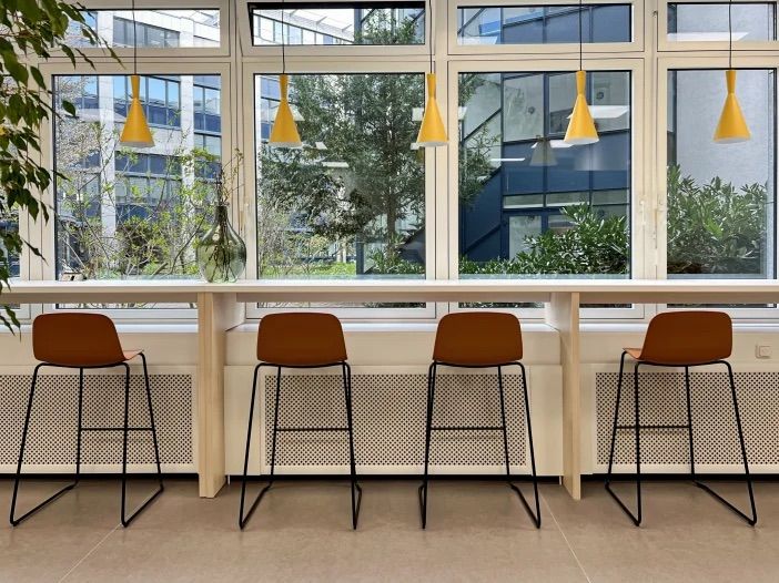 Fensterbereich mit Bartresen, Barhockern und gelben Pendelleuchten